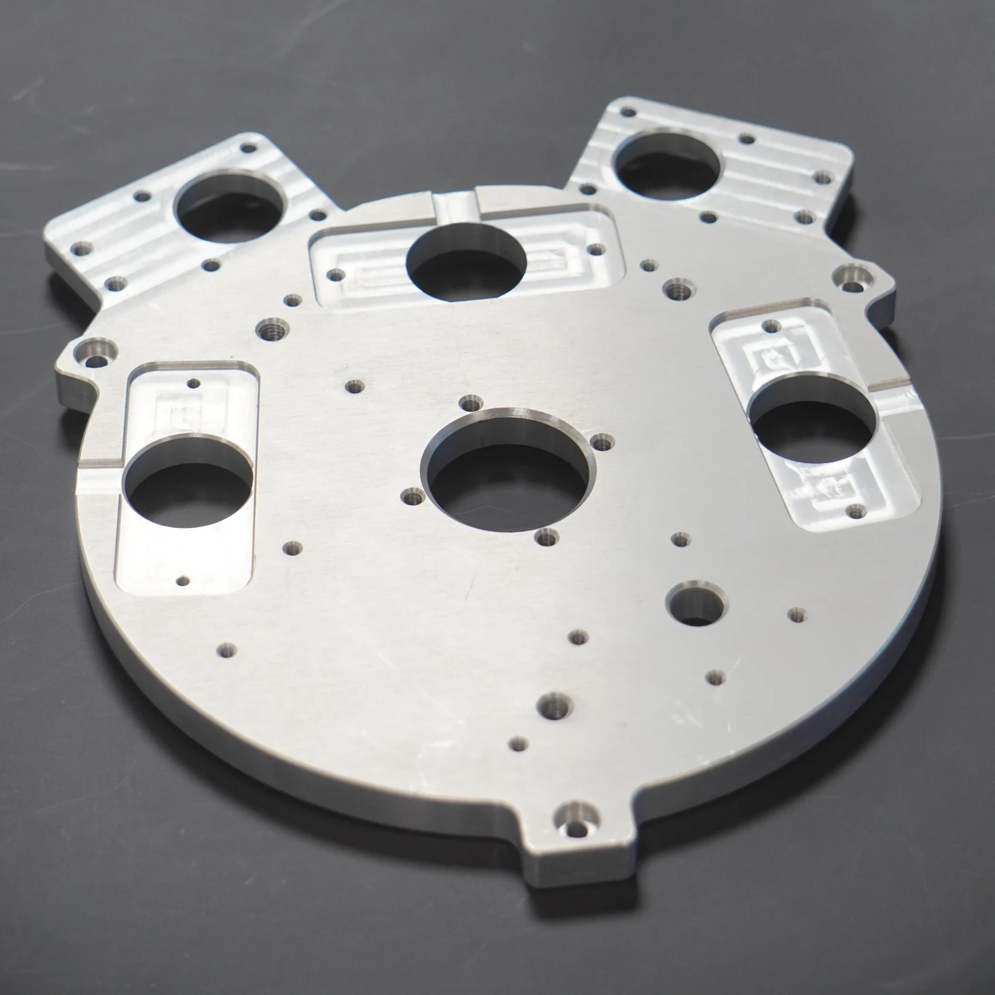 A machined metal plate with holes, pockets and finished surfaces